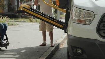 View of an accessible vehicle ramp being lowered to assist a wheelchair user. video