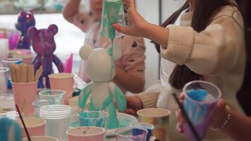 Several teenagers are communicating with each other as they create individual sculptures of bears and paint them during a workshop. video