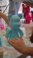 During creation of children's toy in shape of bear, artist generously applied blue paint to create an interesting and beautiful pattern on surface of toy. video