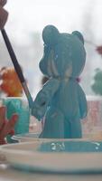 Viscous paint flows down fresh figurines created by the artist in his workshop, in the shape of a bear cub. The artist corrects the drawing with a brush video