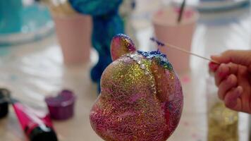 Pink, glamorous teddy bear figurine with tiara made of artificial gems can be turned blue with special stick to create a unique piece of home decor. video