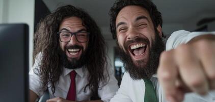 Two bearded men laughing while using a computer photo