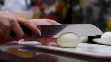 Hands placing sliced boiled eggs on wooden cutting board. Person arranging egg pieces during meal preparation. Fingers carefully handling eggs for kitchen task. Hands organizing food for simple video