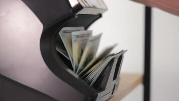 Close-up of US hundred dollar bills stacked in counting machine, emphasizing currency verification, financial accuracy, and banking transaction process video