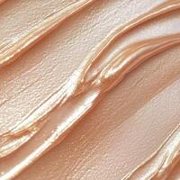 Smooth, shimmering golden cream texture with a metallic finish. Glossy streaks flow across the surface, reflecting soft light. Ideal for skincare, makeup, and cosmetic backgrounds photo