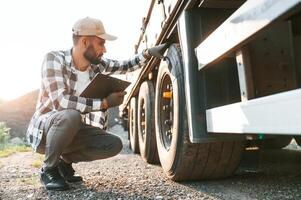 Working with wheels.. Young truck, driver is with his vehicle at daytime photo