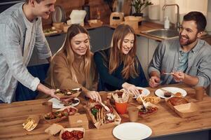 Mea,t, fries,, burger. Friends are sitting indoors at home and eating together photo