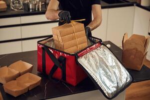On the table. Man packs paper eco boxes into, a bag for food delivery photo
