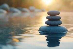 Smooth spa stones on calm water during sunset enhancing relaxation and tranquility in a serene setting. Balancing spa stones are stacked on still water, reflecting the warm glow of the sunset photo