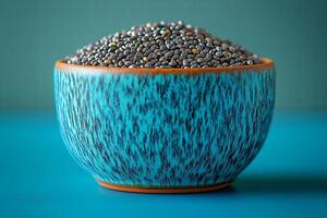 Beautiful turquoise bowl filled with chia seeds on a textured surface perfect for healthy recipes and nutrition inspiration. turquoise bowl overflows with chia seeds against a textured blue background photo