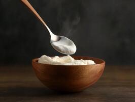 Warm bowl of creamy yogurt with spoon hovering above it photo