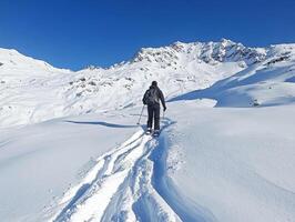 Skiing through untouched snow in alpine mountains on a sunny day photo