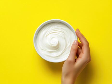 Moisturizing cream application on yellow background photo