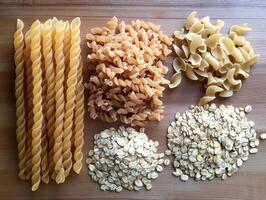 Variety of dried pasta and oats arranged on a wooden surface photo