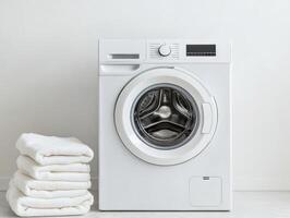 Modern washing machine beside neatly folded white towels photo