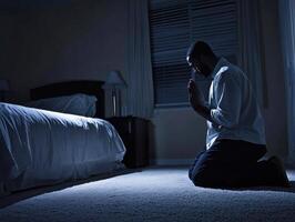 Man kneeling in prayer during nighttime in a quiet room photo