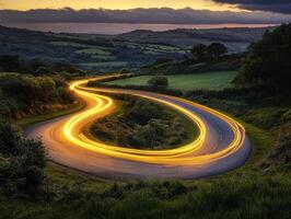 Winding road illuminated by vehicle lights at dusk in the countryside photo
