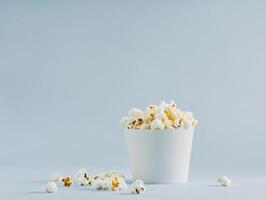 Freshly popped popcorn in a white container with scattered kernels photo
