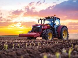 Tractor plowing field at sunset under colorful sky photo