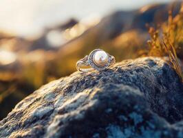 Elegant pearl ring resting on a rock by the water's edge photo