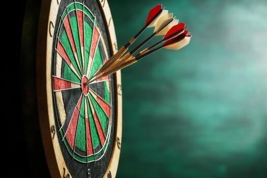 Darts hitting the bullseye on a dartboard with green background photo