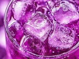 Colorful beverage with ice cubes in a glass on purple background photo