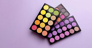 Creative composition of eyeshadow palettes on pastel lavender background in bold trendy beauty flat lay. Multiple eyeshadow palettes featuring vibrant colors arranged in a geometric pattern photo