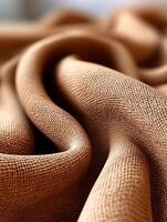 Textured fabric draping elegantly in soft natural light highlighting intricate weave patterns and warm tones. close-up view of beautifully textured fabric draping softly with intricate weave patterns photo