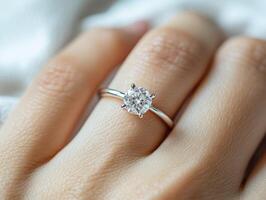 Engagement ring shines on woman's hand with soft fabric background photo