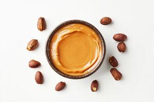 Nut butter in a bowl surrounded by cocoa beans on a white background photo
