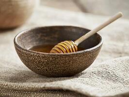 Honey dipper resting in a rustic bowl of golden honey photo