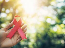 Hand holding a red awareness ribbon in a natural setting photo