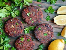 Herbed vegetarian patties with lemon slices on wood photo