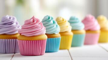 Delicious pastel cupcakes in soft hues displayed on white table, inviting sweetness under gentle daylight. A row of pastel cupcakes in lavender, blush pink, baby blue, and lemon yellow on white table photo