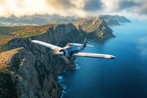Vintage aircraft flies over dramatic coastal cliffs in daylight photo