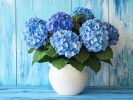 Blue hydrangeas in a white vase on a wooden background photo