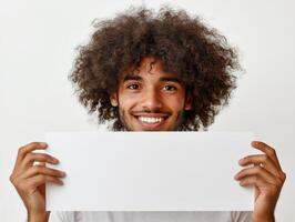 Smiling young man holds blank sign in bright, minimalistic setting photo