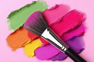 Colorful blush and eyeshadow pigments spread across textured paper with a brush, capturing creative beauty artistry in stunning detail. Blush and eyeshadow pigments scattered on textured paper photo