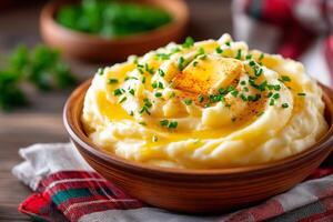 Mashed potatoes topped with melting butter and fresh chives served in a rustic bowl on a linen tablecloth. Creamy mashed potatoes are generously topped with melting butter and freshly chopped chives photo