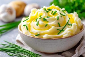 Creamy mashed potatoes with melting butter and fresh chives served in a rustic bowl on a linen tablecloth. mashed potatoes swirl with melting butter topped with fresh chopped chive photo