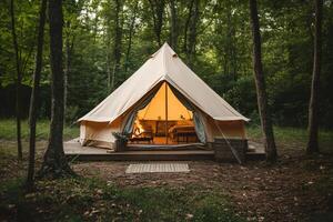 Glamping tent with cozy fireplace illuminating the forest at dusk photo