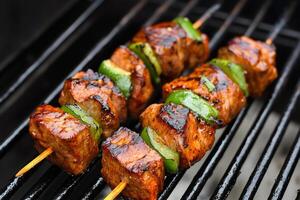Pork and green bell peppers grilling on skewers on a barbecue photo
