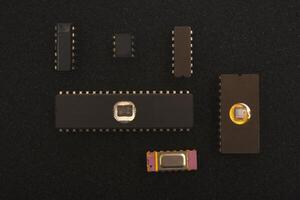 Historical computing hardware assortment. Several microchips on black foam. Old integrated circuits for radio electronics. photo