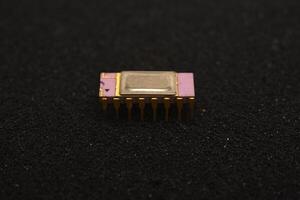 Obsolete PCB components collection. The microcircuit is on black foam. An integrated circuit for radio electronics. photo