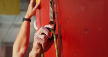 Close-up of securing a lanyard to the hooks on a climbing wall photo