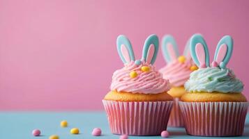 Three cupcakes with bunny ears on a pink background photo