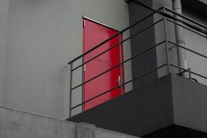 Red emergency door with black iron stairs behind factory building. Industrial fire exit for safety and evacuation. photo