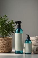 Elegant display of teal spray bottles and a green plant beside neatly rolled towels in a modern setting photo