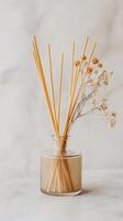 Decoration with aroma sticks in a glass vase combined with dried flowers in a minimalistic setup on a light surface photo