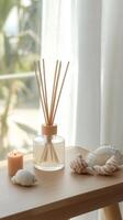 Home decor arrangement with reed diffuser, candle, and seashells by the window during daylight photo